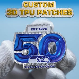 Puede incluir: Un parche de TPU 3D personalizado con el texto "CUSTOM 3D TPU PATCHES". El parche presenta un diseño azul y plateado con el número "50" y el texto "EST 1976". El parche también incluye un logotipo de un pájaro.