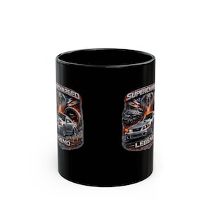May include: A black ceramic mug featuring a graphic print of a silver sports car, a cobra emblem, and a supercharger engine component. The design includes the text SUPERCHARGED LEGEND in bold lettering, set against a background of smoke and fire.