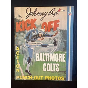 Puede incluir: Una portada de libro de fotos para recortar Johnny Pro Kick Off Baltimore Colts con una ilustración de un jugador de fútbol americano en uniforme azul pateando un balón en un campo verde, con el logo de la NFL y texto rojo y blanco.