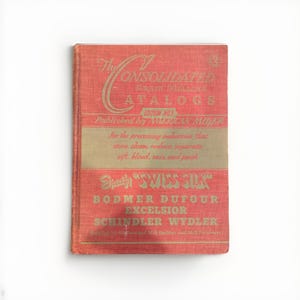 Puede incluir: Un libro antiguo con una cubierta roja y letras doradas. El título dice "The Consolidated Grain Milling Catalogs". El libro es publicado por American Miller y enumera varios procesos de la industria molinera.