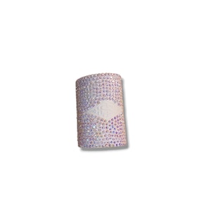 May include: A cylindrical, decorative item covered in iridescent rhinestones. A white, rectangular panel with an embossed design is centered on the item. The rhinestones reflect a range of colours, creating a sparkling effect. The item is set against a white background.