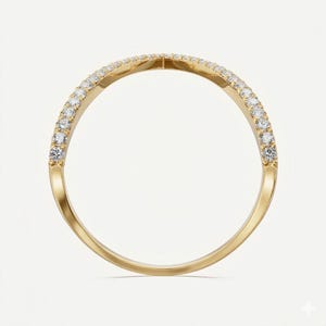 May include: A gold ring with a curved design, set with small, clear gemstones along the top curve. The ring has a polished, shiny finish, and the gemstones are evenly spaced. The ring is shown against a plain white background.