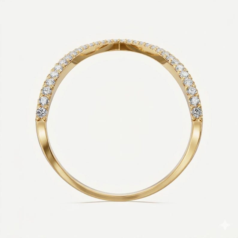 May include: A gold ring with a curved design, set with small, clear gemstones along the top curve. The ring has a polished, shiny finish, and the gemstones are evenly spaced. The ring is shown against a plain white background.