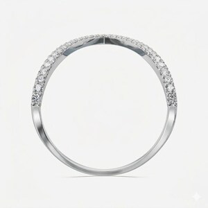 May include: A silver ring with a curved design, set with small, sparkling gemstones along the top half of the band. The ring is displayed against a plain white background, highlighting its elegant simplicity.