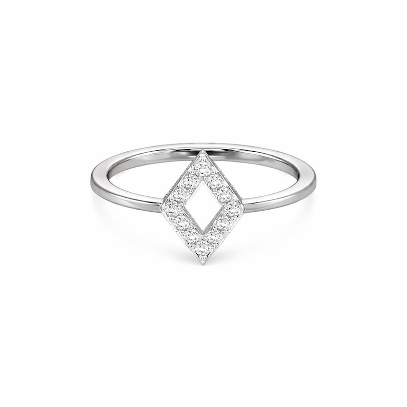 May include: A silver ring featuring a diamond-shaped design. The diamond shape is filled with small, sparkling stones, creating a dazzling effect. The ring band is a simple, polished silver.