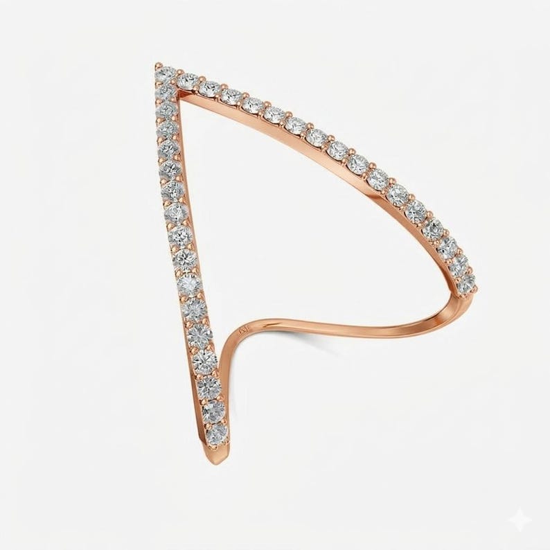 May include: A rose gold ring with a unique, open design. The ring features a row of small, clear gemstones along the edges of the open triangle shape. The ring curves around to form a band.