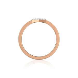 May include: Rose gold ring with a small, rectangular top set with small, clear stones. The band is a simple, rounded design. The ring is shown against a white background.