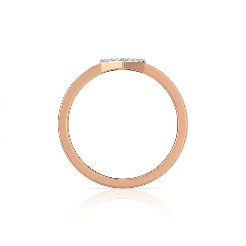 May include: Rose gold ring with a small, rectangular top set with small, clear stones. The band is a simple, rounded design. The ring is shown against a white background.