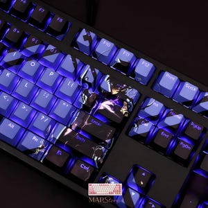 Könnte beinhalten: Schwarze mechanische Tastatur mit blau beleuchteten Tasten. Einige Tasten haben ein individuelles Design mit einem Charakter und einem Blitz-Effekt. Die Tastatur hat ein Standard-Layout mit Funktionstasten und einem Nummernblock. Der Markenname "MAPStore" ist sichtbar.