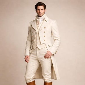 May include: A cream-colored, three-piece suit with a long coat, vest, and trousers. The coat features gold buttons and a high collar. The outfit is paired with a white shirt and a patterned necktie. The person is wearing brown boots.