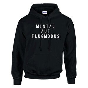 Op de afbeelding: Zwarte hoodie met de witte tekst "MENTAL AUF FLUGMODUS". De sweatshirt heeft een voorzak en een capuchon met trekkoord. Het Gildan-logo is zichtbaar op de capuchon.