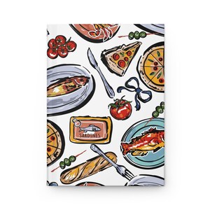 Op de afbeelding: Een wit notitieboek met een kleurrijke illustratie van diverse voedingsmiddelen. Het ontwerp bevat pizzapunten, sardines, tomaten, olijven en een baguette, waardoor een levendig en smakelijk patroon ontstaat.