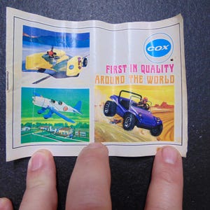 May include: A vintage paper advertisement featuring illustrations of a yellow airplane, a blue and white airplane, and a purple dune buggy. The text reads "COX FIRST IN QUALITY AROUND THE WORLD."