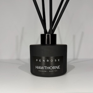 May include: A distressed white wooden sign displaying the word "Welcome" in a handwritten font. A small heart decoration is affixed below the text. The background is a blurred image of a wooden surface, suggesting a rustic aesthetic.