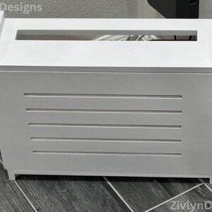 Puede incluir: Una caja de madera blanca con una abertura rectangular en la parte superior y ranuras horizontales en la parte delantera. La caja est&aacute; dise&ntilde;ada para ocultar cables y alambres. La caja mide aproximadamente 51 cm de ancho, 30 cm de profundidad y 36 cm de alto.