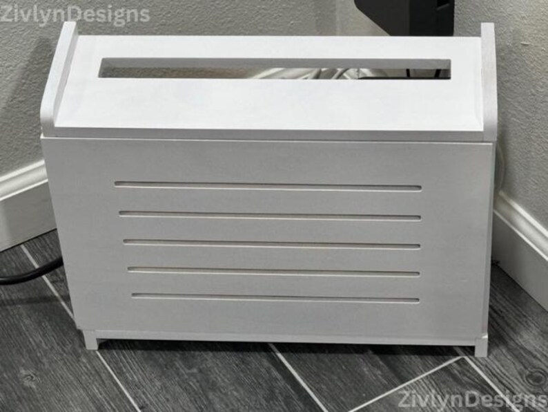Puede incluir: Una caja de madera blanca con una abertura rectangular en la parte superior y ranuras horizontales en la parte delantera. La caja est&aacute; dise&ntilde;ada para ocultar cables y alambres. La caja mide aproximadamente 51 cm de ancho, 30 cm de profundidad y 36 cm de alto.