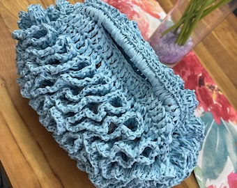 Bolso artesanal de rafia azul cielo, tejido a mano con un diseño único y sofisticado.