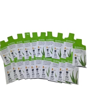 Puede incluir: Un conjunto de sobres de Herbal Aloe Concentrate de Herbalife. Cada sobre es blanco con detalles verdes y presenta el logotipo de Herbalife, el nombre del producto e ilustraciones de hojas de aloe vera. Cada sobre contiene 15 ml.