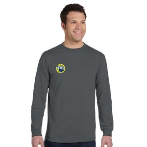 Könnte beinhalten: Ein anthrazitfarbenes Langarmshirt mit einem kleinen kreisförmigen Logo auf der linken Brust. Das Logo zeigt die Buchstaben "LWU" in Marineblau und Weiß vor einem gelb-blauen Hintergrund. Das Shirt ist aus weichem Material.