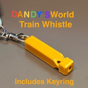 Puede incluir: Un silbato de tren amarillo brillante con el texto "DANDY'S World Train Whistle" y "Includes Keyring". El silbato es rectangular con bordes redondeados y un pequeño agujero en un extremo. Está unido a un llavero plateado.