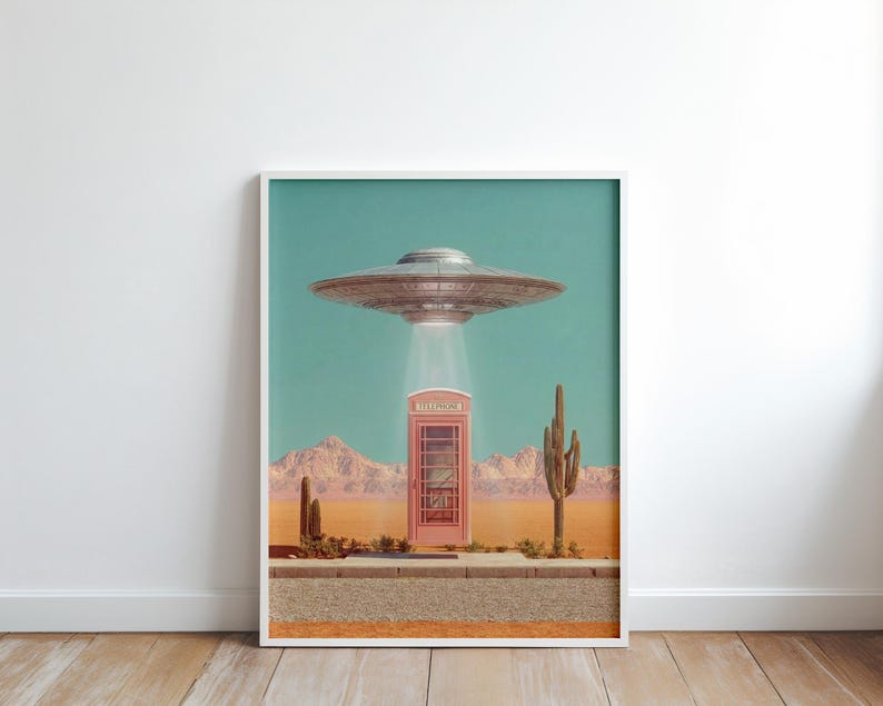 May include: A framed art print featuring a retro-style scene with a pink telephone booth in a desert landscape. A silver UFO hovers above, emitting a bright light. The background includes mountains, cacti, and a teal sky.