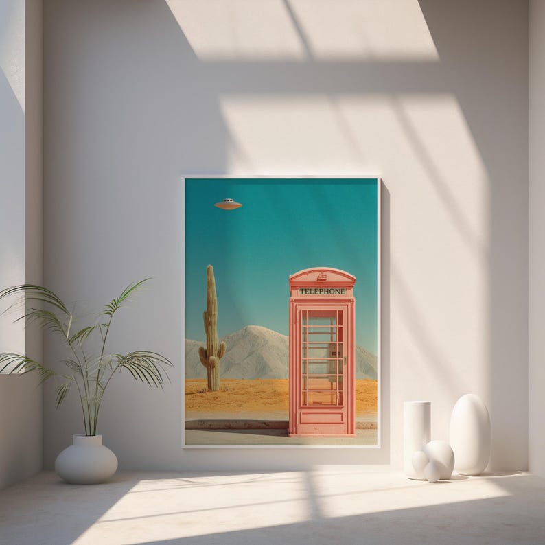 May include: A framed art print featuring a pink telephone booth in a desert landscape with a cactus and a UFO. The word "TELEPHONE" is printed on the top of the booth. The sky is teal.