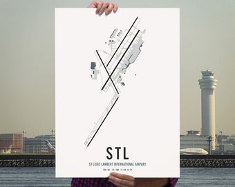 May include: A black and white print of the St. Louis Lambert International Airport (STL) runway layout. The print features the airport code "STL" and the airport name below the runway layout.