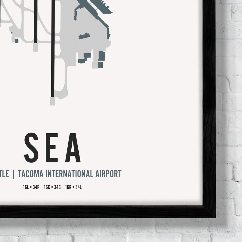 K&ouml;nnte beinhalten: Eine Schwarzwei&szlig;karte eines Flughafens mit dem Text "SEA" und "Seattle | Tacoma International Airport" darunter. Die Karte zeigt die Anordnung des Flughafens mit Start- und Landebahnen sowie Rollwegen. Der Text "16L &bull; 34R 16C &bull; 34C 16R &bull; 34L" befindet sich unter dem Flughafennamen.