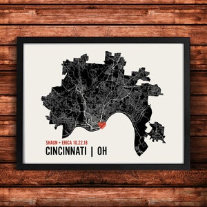 May include: A black and white map of Cincinnati, Ohio with a red heart marking the location of Shaun and Erica's wedding. The text below the map reads "Shaun + Erica 10.22.18 Cincinnati | OH".