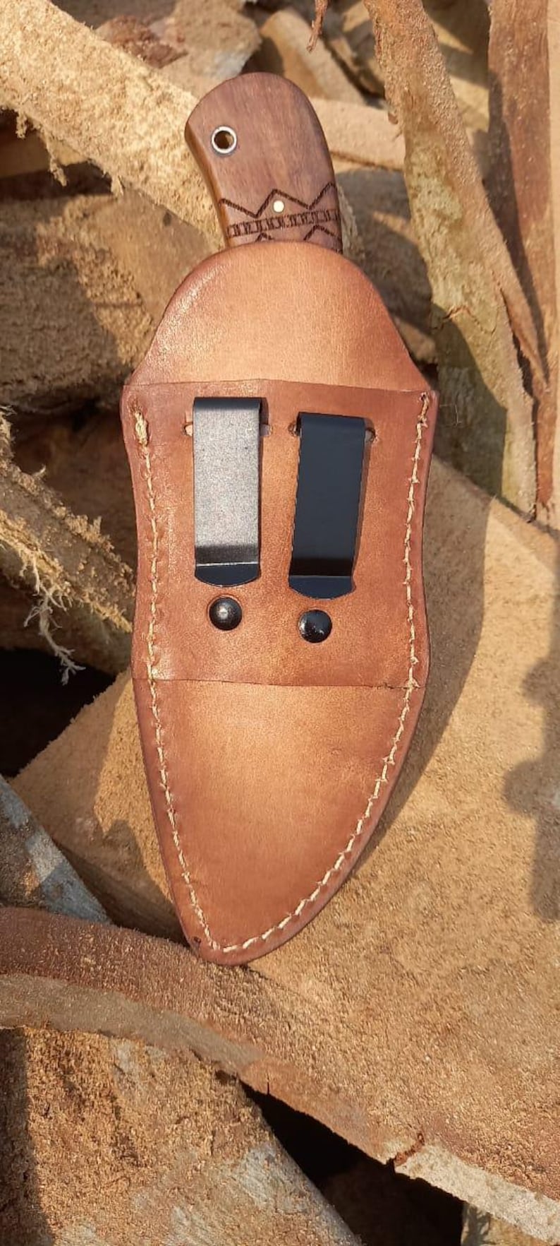 May include: A white ceramic mug with a black handle and the text "But First, Coffee" in a bold, black font. The mug is set against a blurred background, suggesting a cozy setting.