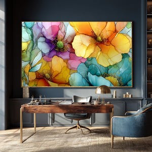 May include: A large framed floral art print featuring vibrant, abstract flowers in shades of yellow, orange, pink, purple, and blue. The artwork is displayed above a wooden desk with a gold lamp and a blue armchair.