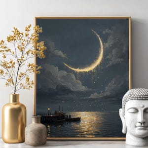 May include: A framed art print depicts a crescent moon over a body of water. The moon is golden and luminous, with light reflecting on the water. The artwork is framed in gold and is displayed with a gold vase, a small stone vase, and a white Buddha head.