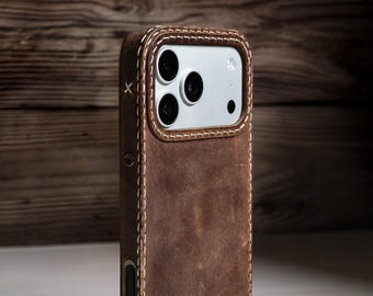 May include: A brown leather phone case with white stitching and a silver camera module. The case has a rugged, textured appearance and a stitched border. The phone case is designed to protect the phone.