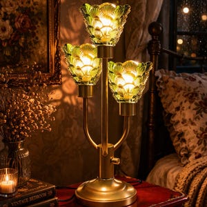 Vintage tafellamp met 3 lichtpunten, groene glazen kap met bloemenmotief, nachtlampje met gouden voet, gezellige nachtverlichting, woondecoratie in antieke stijl.