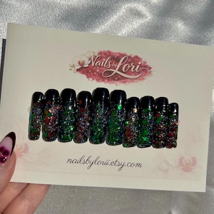 Könnte beinhalten: Zehn schwarze Press-On-Nägel mit einem Glitzer-Farbverlauf in Rot, Grün und schillernden Farben. Die Nägel werden auf einer Karte mit dem Text "Nails by Lori" und der Etsy-Shop-URL präsentiert.