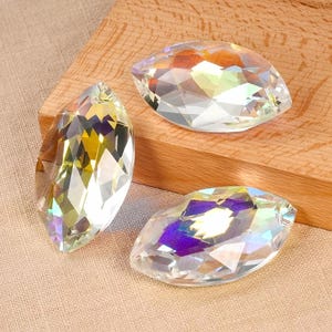 May include: Three iridescent crystal teardrop shaped pendants. The crystals are clear with rainbow colors reflecting off the facets.