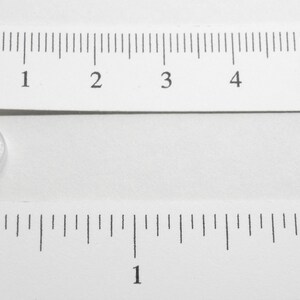 Pu&ograve; includere: Un bottone rotondo in plastica trasparente con un diametro di circa 1,25 cm.