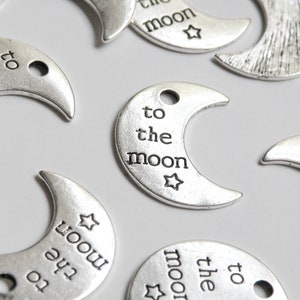 May include: Silver crescent moon charms with the text "to the moon" and a small star.