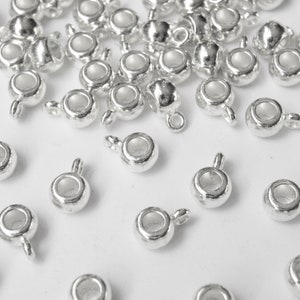 May include: Silver-toned metal bead caps with a loop on one end. The bead caps are designed to be used with jewelry making.