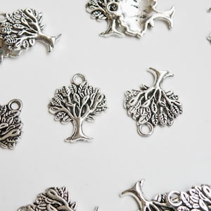 May include: A collection of silver metal tree charms with intricate details. The charms are perfect for adding a touch of nature to jewelry, crafts, and other projects.