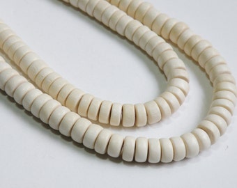 May include: A strand of off-white wooden beads, strung together to form a necklace. The beads are round and have a smooth, polished finish.