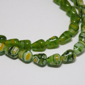 May include: A strand of green glass beads with white and yellow swirls. The beads are teardrop shaped and have a glossy finish.