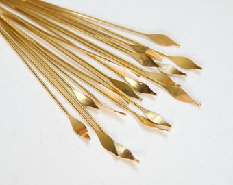 May include: A bunch of gold-colored metal craft wire with pointed ends. The wire is arranged in a fan shape.
