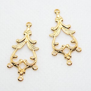 May include: Two gold-tone metal decorative embellishments with a filigree design. Each embellishment has three loops at the bottom.