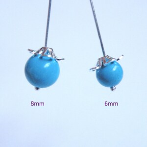 May include: Two turquoise beads with silver-colored accents. One bead is 8mm in diameter, and the other is 6mm. The beads are on silver-colored pins, perfect for jewelry making or crafting projects.