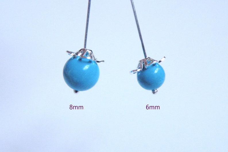 May include: Two turquoise beads with silver-colored accents. One bead is 8mm in diameter, and the other is 6mm. The beads are on silver-colored pins, perfect for jewelry making or crafting projects.