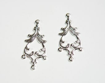 May include: Two silver filigree metal charms with a decorative design. Each charm has a loop at the top for attaching to a necklace or bracelet.