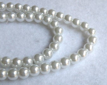 May include: A strand of white pearl beads. The beads are round and smooth, and they are strung on a clear thread.