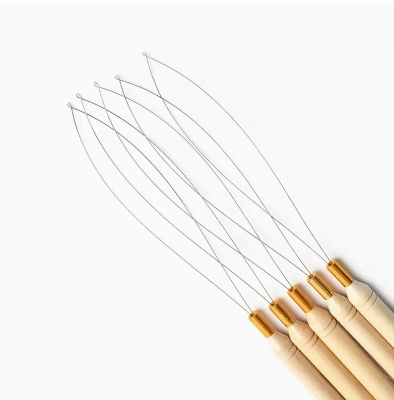 May include: A set of six hair extension tools. Each tool has a thin, silver wire loop attached to a wooden handle with a gold-colored metal ferrule. The tools are arranged diagonally against a white background.