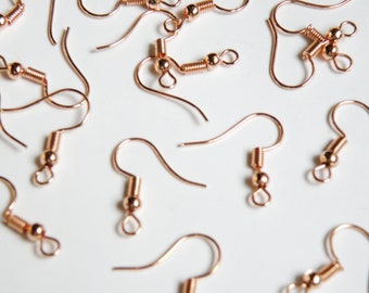 May include: A close-up of a group of rose gold earring hooks. The hooks are made of metal and have a spring-loaded closure.